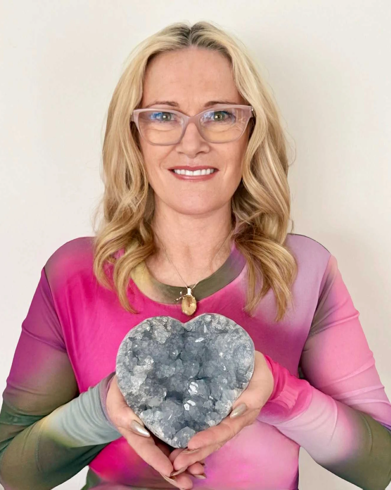Felicity, smiling, holding a grey crystal heart in both hands